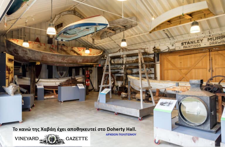 Maritime museum interior showing old wooden boats suspended from the ceiling and vintage gear on display stands.