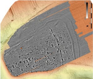 Top-down sonar/bathymetric view of a sunken rectangular shipwreck on the seabed, with the hull shaded gray and surrounding seabed in orange and yellow; a scale bar is visible on the right.