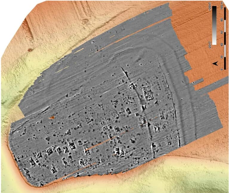 Top-down sonar/bathymetric view of a sunken rectangular shipwreck on the seabed, with the hull shaded gray and surrounding seabed in orange and yellow; a scale bar is visible on the right.