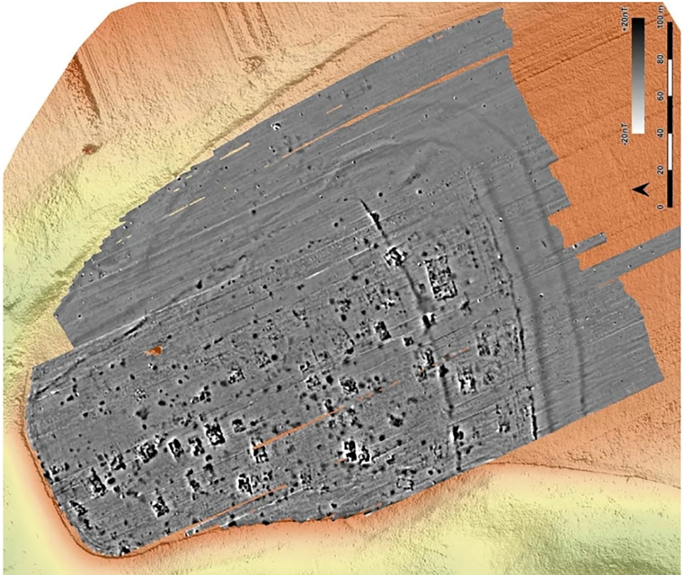 Top-down sonar/bathymetric view of a sunken rectangular shipwreck on the seabed, with the hull shaded gray and surrounding seabed in orange and yellow; a scale bar is visible on the right.