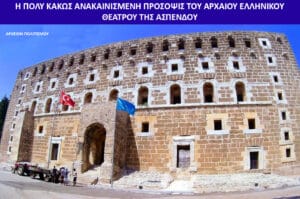 Large stone fortress with many arched windows and flags at the entrance, with people and a trailer nearby.