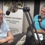 Two men sit at a radio studio table, speaking into large microphones with a laptop and banner in the background.