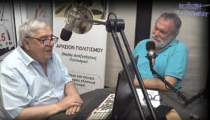 Two men sit at a radio studio table, speaking into large microphones with a laptop and banner in the background.