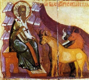 Orthodox icon: haloed saint with cross sits on a throne, blessing a deer and a cow nearby.