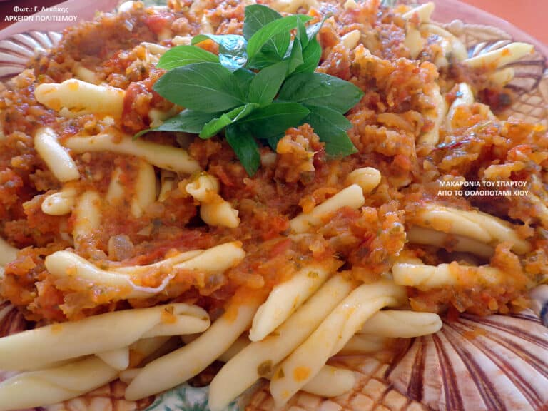 Pasta with a chunky tomato-meat sauce and a sprig of fresh basil on top.