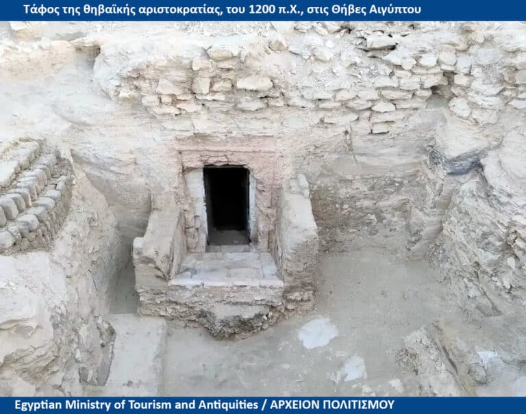 Excavated ancient tomb entrance in a stone shaft, surrounded by earth and rubble.
