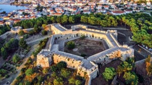 A star‑shaped fortress with pale stone walls on a hill overlooking a town and harbor.