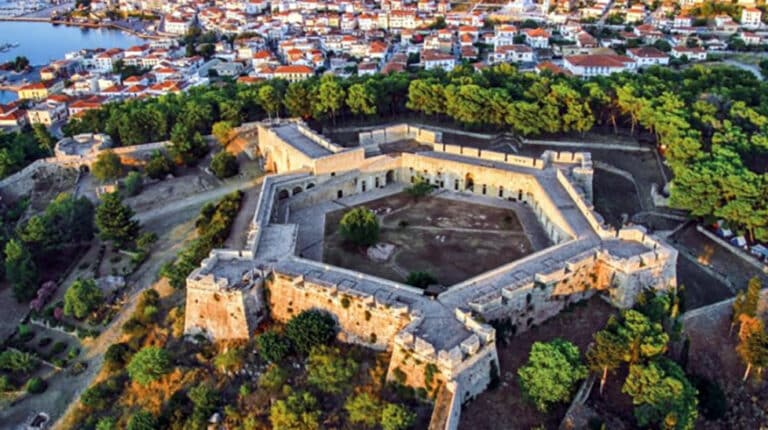 A star‑shaped fortress with pale stone walls on a hill overlooking a town and harbor.