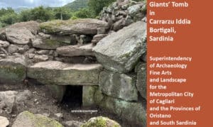 Entrance to Giants' Tomb, a megalithic stone structure with a dark entrance among mossy rocks in Sardinia