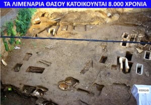 Archaeological excavation site with many square and rectangular pits in dirt, and a trench running through the area, edges of greenery nearby.