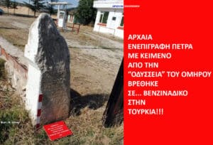 Weathered stone stele beside a red-and-white post with a small red plaque on the ground and a building in the background, plus a bright red article banner on the right.