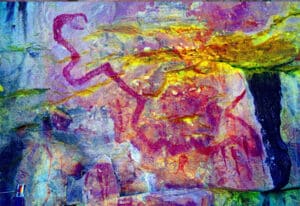 Rock wall covered in bright, multicolored abstract graffiti and red line drawings.