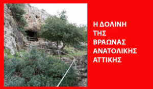 Rocky hillside with a cave entrance, metal railing along stone steps, and surrounding shrubs.