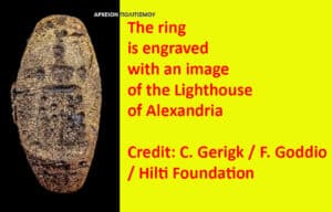 Ancient oval ring with a carved face on a black background; a bright yellow panel beside it notes the ring is engraved with the Lighthouse of Alexandria and credits.