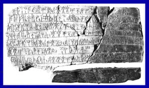 Fragmented ancient stone tablet with horizontal rows of inscriptions, cracked in two and resting on a white background.